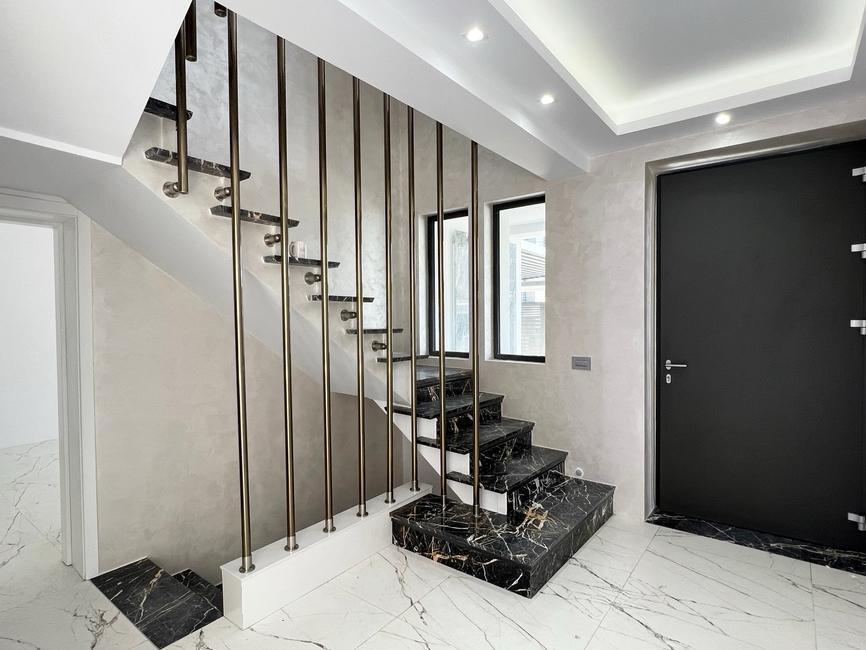 Elegant entrance hall with marble staircase and bespoke metal balustrade